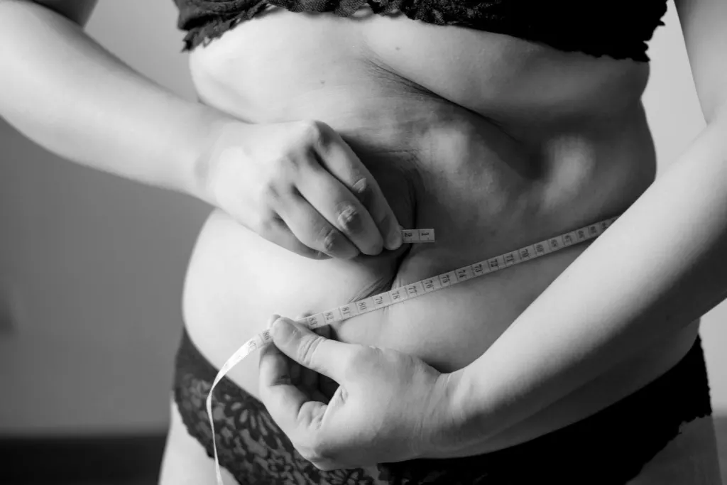 Mujer pellizcando la piel del abdomen