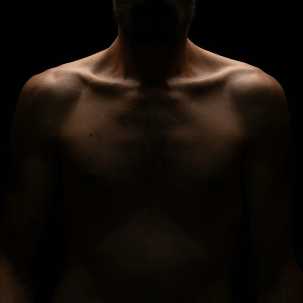 Hombros y pecho de un hombre en penumbra